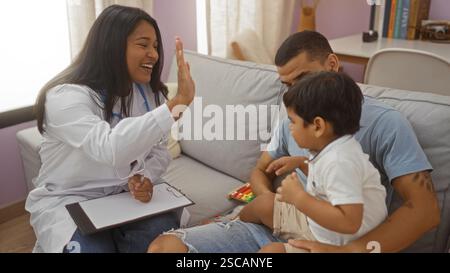 Kinderärztin High-Fiving mit Vater und Sohn im Wohnzimmer während des Hausbesuchs mit Interaktionen und Indoor-Sprechstunden Stockfoto