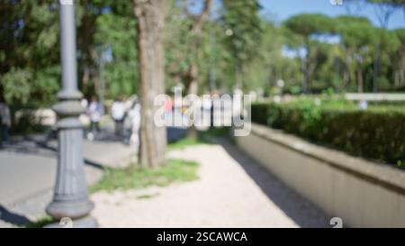 Verschwommenes Bild von Menschen, die zwischen Bäumen und Grün in den Gärten der Villa borghese in rom spazieren und eine friedliche Atmosphäre im Freien mit defokussierter Feige betonen Stockfoto