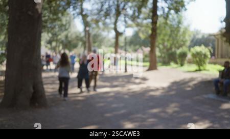 Unscharfe Menschen schlendern in den Gärten der Villa borghese in rom, umgeben von üppigem Grün und sanftem Sonnenlicht in einer urbanen Umgebung im Freien mit einer zwanglosen Atmosphäre Stockfoto