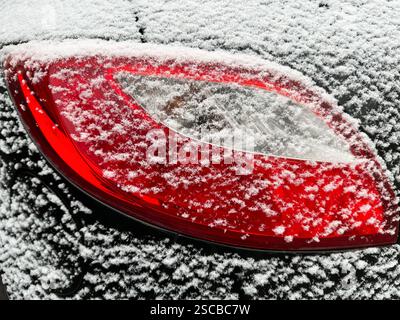 Hintergrundbeleuchtung eines Autos, das im Winter mit Schnee bedeckt ist Stockfoto