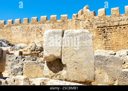 Stein mit einer Inschrift und anderen Ruinen von Lindos auf der Insel Rhodos in der Dodekanese, Griechenland. Stockfoto