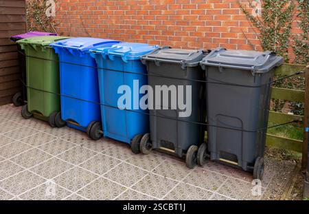 UK Recycling-Mülltonnen in verschiedenen Farben, die im Gartenlagerbereich angeordnet sind. Stockfoto