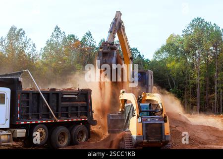 Schwere Maschinen transportieren während der Herbstsaison Boden und Schutt auf der Baustelle, umgeben von Bäumen. Stockfoto