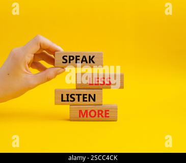 Weniger sagen, mehr hören. Holzblöcke mit Wörtern sprechen weniger Hören Sie mehr. Schöner gelber Hintergrund. Geschäftsmann Hand. Geschäftlich und weniger sprechen Stockfoto