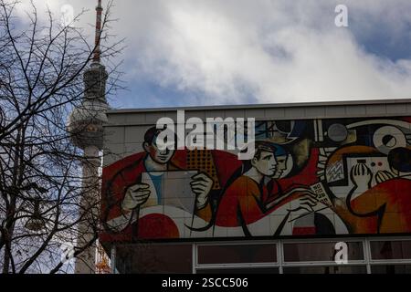 Sozialistischer Realismus 31012025 - das Pressehaus am Alexanderplatz wurde 1970 1973 als Haus des Berliner Verlages nach den Plänen der Architekten Karl-Ernst Swora, Rainer Hanslik, Günter Derdau, Waldemar Seifert und Gerhard Voss erbaut. Es entstand als Konkurrenz zum 1965 in West-Berlin fertiggestellt Axel-Springer-Hochhaus. An seiner Fassade sind Kunstwerke des sozialistischen Realismus zu sehen. Im Hintergrund der Fernsehturm Berlin Berlin Deutschland *** Sozialistischer Realismus 31012025 das Pressehaus am Alexanderplatz wurde 1970 als Berliner Verlag nach Plänen von AR erbaut Stockfoto