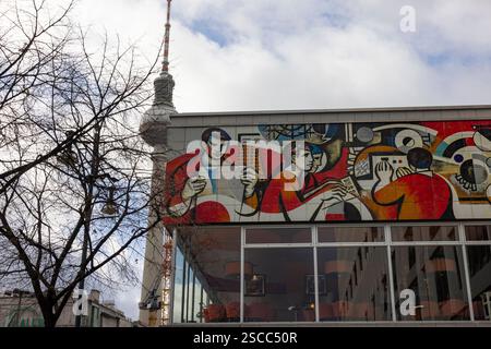 Sozialistischer Realismus 31012025 - das Pressehaus am Alexanderplatz wurde 1970 1973 als Haus des Berliner Verlages nach den Plänen der Architekten Karl-Ernst Swora, Rainer Hanslik, Günter Derdau, Waldemar Seifert und Gerhard Voss erbaut. Es entstand als Konkurrenz zum 1965 in West-Berlin fertiggestellt Axel-Springer-Hochhaus. An seiner Fassade sind Kunstwerke des sozialistischen Realismus zu sehen. Im Hintergrund der Fernsehturm Berlin Berlin Deutschland *** Sozialistischer Realismus 31012025 das Pressehaus am Alexanderplatz wurde 1970 als Berliner Verlag nach Plänen von AR erbaut Stockfoto