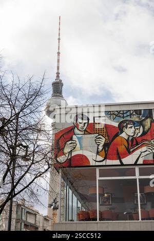 Sozialistischer Realismus 31012025 - das Pressehaus am Alexanderplatz wurde 1970 1973 als Haus des Berliner Verlages nach den Plänen der Architekten Karl-Ernst Swora, Rainer Hanslik, Günter Derdau, Waldemar Seifert und Gerhard Voss erbaut. Es entstand als Konkurrenz zum 1965 in West-Berlin fertiggestellt Axel-Springer-Hochhaus. An seiner Fassade sind Kunstwerke des sozialistischen Realismus zu sehen. Im Hintergrund der Fernsehturm Berlin Berlin Deutschland *** Sozialistischer Realismus 31012025 das Pressehaus am Alexanderplatz wurde 1970 als Berliner Verlag nach Plänen von AR erbaut Stockfoto