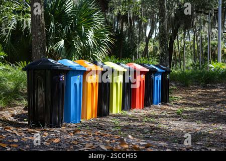 In einem Park stehen eine Reihe von Mülltonnen. Die Mülleimer haben verschiedene Farben, einschließlich Schwarz, Blau, Gelb und Rot. Konzept der Organisation an Stockfoto