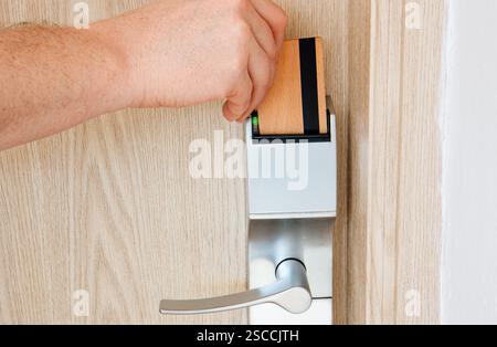 Man Hotelgast mit Holzschlüsselkarte, um die Hotelzimmertür in einem umweltfreundlichen, umweltfreundlichen und nachhaltigen Lifestyle-Hotel zu öffnen. Stockfoto