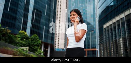 Eine kompetente und ehrgeizige Geschäftsfrau führt ein Telefongespräch in einer städtischen Umgebung Stockfoto