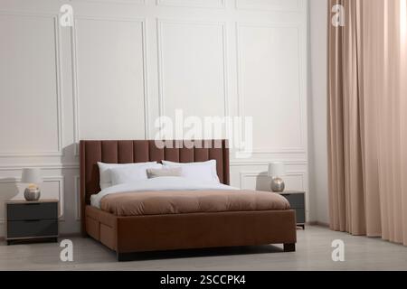 Großes Bett in Mokkahaumschatten und Nachttische drinnen. Trendige Farbe 2025 Jahre im Innendesign Stockfoto
