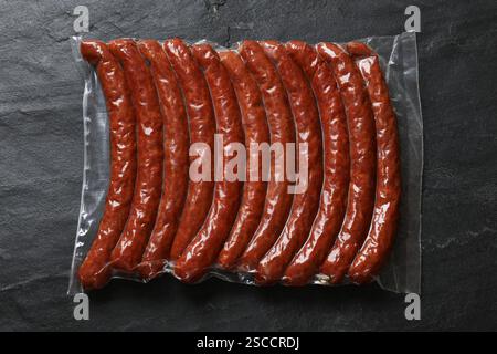 Packung geräucherte Würstchen auf schwarzem Tisch, Draufsicht Stockfoto