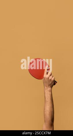 Rotes Tischtennispaddel mit gestrecktem Zeigefinger, das Technik und Präzision in Wettkampfspielen vor beigefarbenem Hintergrund betont. Stockfoto