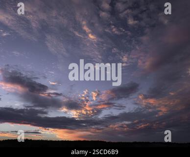 Ein atemberaubender Himmel bei Sonnenuntergang mit dramatischen, pastellfarbenen Wolken, die warme und kühle Töne in einer ruhigen, aber dynamischen Komposition vermischen. Stockfoto