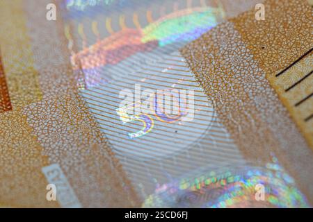 Nahaufnahme einer 50-Euro-Banknote mit Schwerpunkt auf den irisierenden Sicherheitsmerkmalen und der Zahl „50“. Der Hintergrund zeigt ein kompliziertes, sich wiederholendes Muster Stockfoto