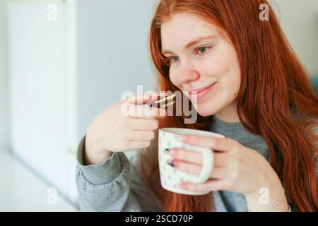 Mädchen mit rotem Haar isst Schokolade mit Pistazienfüllung Stockfoto