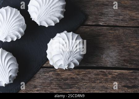 Weiße Meringues auf schwarzem Schieferteller auf hölzernem Hintergrund Stockfoto