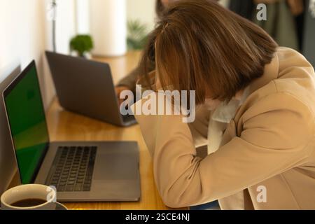 Verzweifelte Frau, die ihren Kopf vor einem Laptop in einem Café hält, in einem Café arbeitet Stockfoto