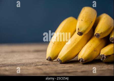 Ein Haufen frischer reifer Bananen auf rustikalen Holzbrettern auf blauem Hintergrund. Stockfoto