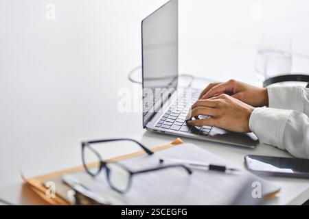 Geschäftsfrau, die im Büro am Computer arbeitet. Handtippen auf Laptop am Schreibtisch Stockfoto