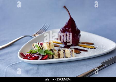 Pochierte Birne mit Schokoladenkuchen, Eis und Erdbeere auf einem Teller mit Minze, Dessert Stockfoto