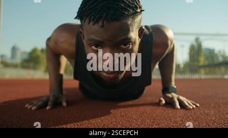 Sportlicher Bodybuilder afroamerikanischer Sportler junger Mann, der Liegestützübungen auf Fußballstadion macht männliche starke Athlet Fitness Training Muskeln Stockfoto