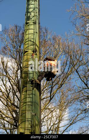 Der Mann klettert an einer Stange und arbeitet daran Stockfoto