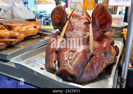 Das Schmoren ist eine traditionelle chinesische Kochtechnik mit einer langen kulinarischen Geschichte, die hier mit einem Gericht aus Schweinekopf und Entenfleisch im Hintergrund zu sehen ist Stockfoto