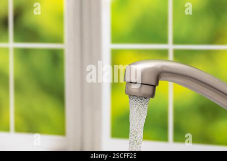 Wasser fließt aus dem Küchenarmatur. Wassereinsparung, Knappheit und sicheres sauberes Trinkwasser. Stockfoto