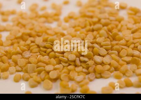 Getrocknete gelbe Spalterbsen werden auf einer Ebenen Oberfläche verteilt und zeigen ihre lebendige Farbe und Textur, ideal für Rezepte. Stockfoto