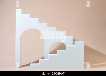 Geometrische Formen Treppen Podeste und Bögen stehen auf einem beigefarbenen Hintergrund Stockfoto