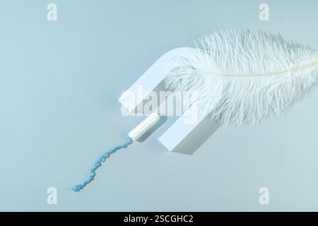Ein weiblicher Hygiene-Baumwolltampon auf einer hellrosa Feder liegend als Frischebegriff Stockfoto