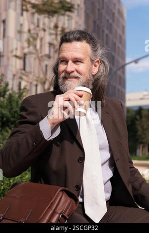 Erfolgreicher reifer Mann trinkt Kaffee zum Mitnehmen Stockfoto
