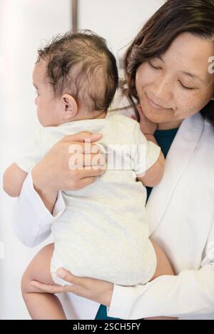 Nahaufnahme des Arztes, der das Baby hält und auf den Rücken blickt Stockfoto
