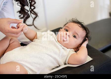 Nahaufnahme des Babys, das sich niederlegt und die Hand des Arztes hält Stockfoto