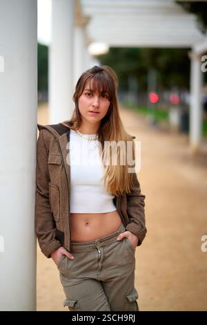 Die junge Frau posiert im Freien in lässiger Kleidung in der Nähe weißer Säulen Stockfoto