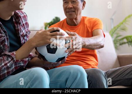 Asiatischer Vater und Sohn teilen sich zu Hause einen Fußball und betonen die familiäre Verbindung und Teamarbeit. Stockfoto