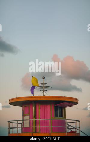 Ein malerischer Blick auf einen lebendigen, farbenfrohen Rettungsschirm-Turm am Miami Beach, der bei Sonnenuntergang unter einem sanft beleuchteten Himmel gefangen gehalten wird. Dieses Bild enthält Pastellfarben Stockfoto