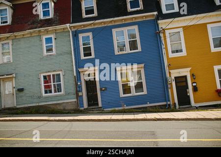 Leuchtend blaue, gelbe und grüne Reihenhäuser säumen eine ruhige Straße in St. John's, Neufundland und Labrador, die einzigartige architektonische Details und Cha zeigen Stockfoto