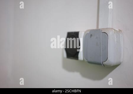 Zwei Steckdosen sind an der Wand montiert, eine weist Verschleiß auf, die andere ist sauber. Die Einrichtung ermöglicht Geräteverbindungen in einem leisen RO Stockfoto