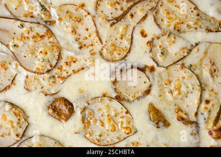 Eine Nahaufnahme einer Gourmet-Birnen- und Gorgonzola-Auberginen-Pizza mit geschmolzenem Käse und Birnenscheiben, garniert mit gerösteten Nüssen. Stockfoto