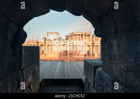Das majestätische antike römische Theater von Merida, Spanien, durch einen Steinbogen, der seine historischen Säulen umrahmt, die in goldenes Sonnenlicht getaucht sind, und fängt die ess ein Stockfoto