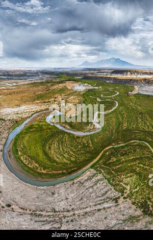 Ein atemberaubendes Drohnenfoto fängt einen sich windenden Fluss ein, der sich durch das zerklüftete Gelände von Hanksville, Utah schlängelt, und zeigt das kontrastreiche ver Stockfoto