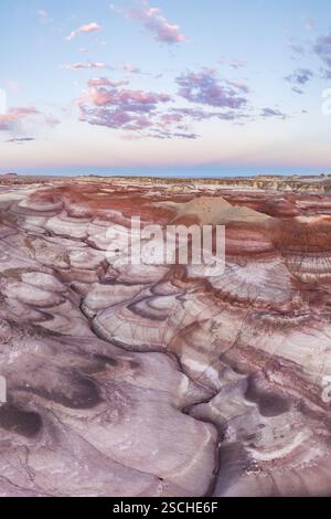 Fesselndes Luftbild der verwinkelten und bunten Bentonithügel in Utah, USA, unter einem Himmel, der bei Sonnenuntergang von sanften rosa Wolken bedeckt ist. Stockfoto