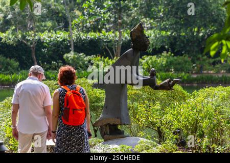 Besucher, die sich die Swing Me Mama Kunstskulptur aus Schaukelstein ansehen, sind auf einem Tourismusausflug in den Botanischen Gärten von Singapur zu Gast. Künstlerische Wertschätzung. Stockfoto