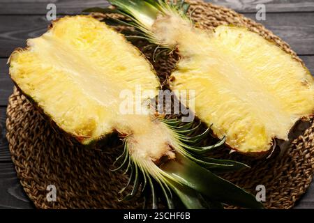 Hälften reifer Ananas auf schwarzem Holztisch, Nahaufnahme Stockfoto