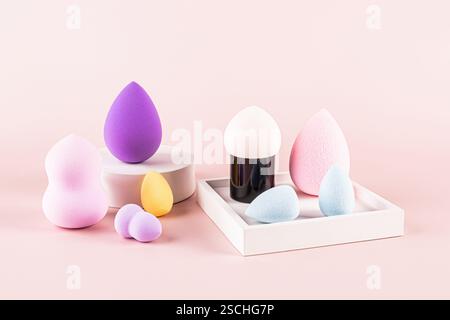Verschiedene bunte Make-up-Schwämme und ein Schönheitsmixer sind ordentlich angeordnet. Das Bild zeigt verschiedene Formen und Größen von Schwämmen, die auf einem hellen p dargestellt werden Stockfoto