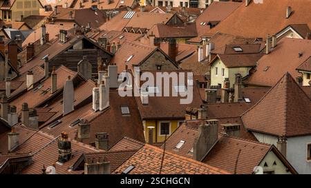 Ein Luftbild, das ein Labyrinth aus ineinander greifenden Terrakotta-Dächern und Schornsteinen in Annecy, Frankreich, einfängt, hervorgehoben durch sanftes Sonnenlicht. Stockfoto