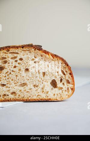 Nahaufnahme einer frisch geschnittenen Scheibe Sauerteigbrot mit luftiger Textur und knusprigem Rand. Stockfoto