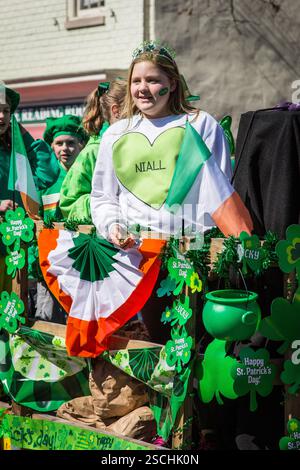 St. Patrick's Day-Paradewagen. Kinder in Grün, Flaggen und ein NIALL-Sweatshirt. Werfen Sie Konfetti. Stockfoto